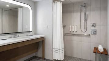 A modern bathroom with a shower, a vanity with a mirror, and a towel rack.