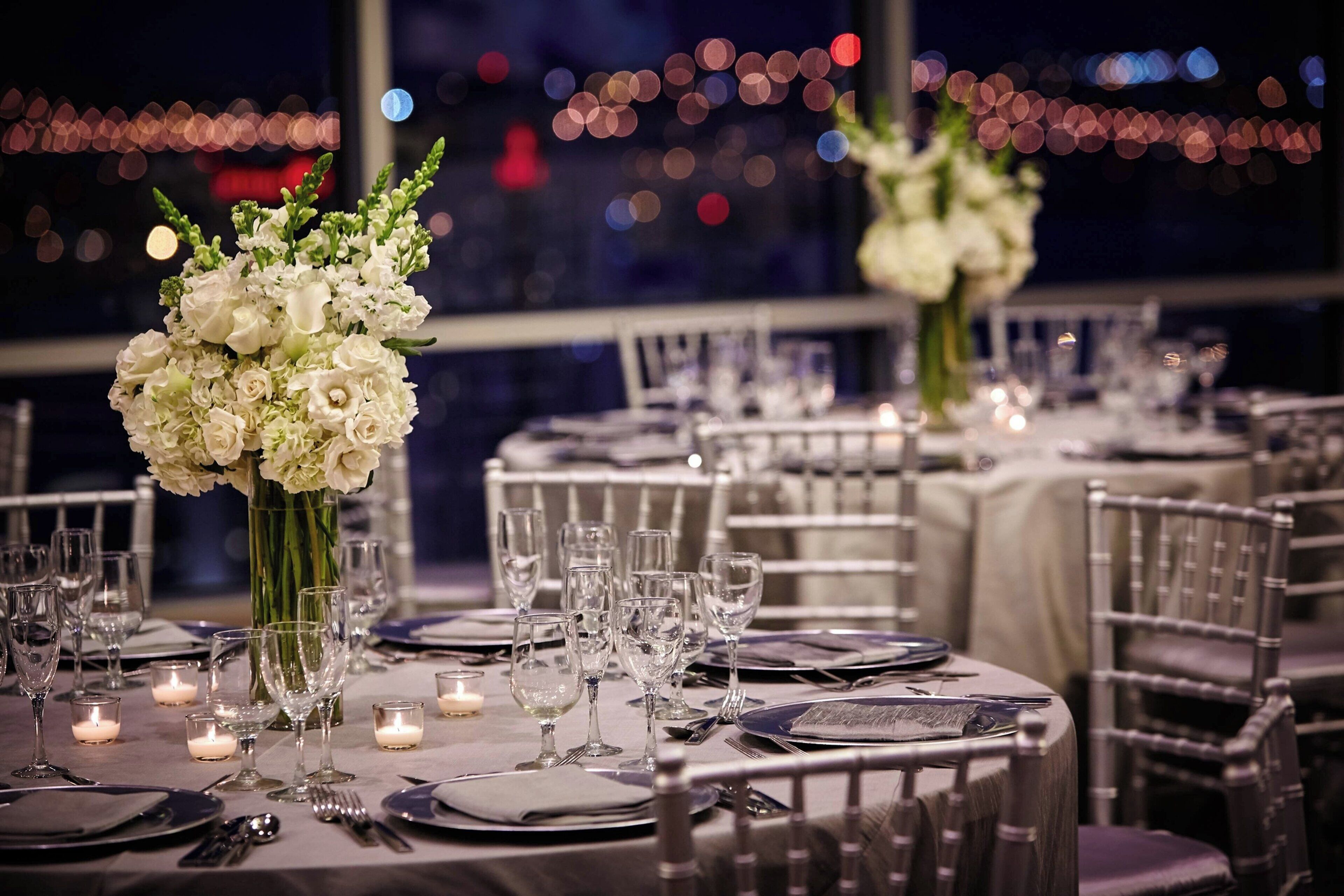 A restaurant table set with white flowers, candles, and glassware.