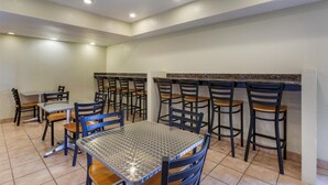 A dining area with tables and chairs, a kitchen counter, and a tiled floor. - SureStay by Best Western Chambers Petrified Forest (Chambers)