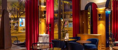 A cozy interior with a bar area, red curtains, and a view of the street outside.