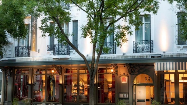 Un hotel con fachada clásica, zona de estar al aire libre y un letrero que indica que es un hotel.