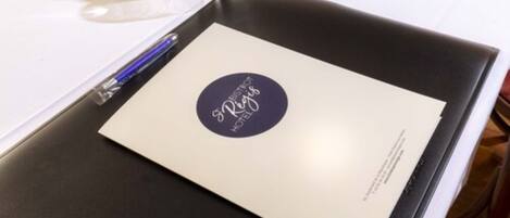 A hotel brochure on a table with a pen and a glass of water.