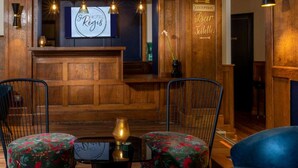 Un área de recepción con un mostrador de madera, dos sillones con tapicería floral, un cartel que dice "HOTEL Régis" y un letrero que indica "RECEPTION Bar Toilettes".