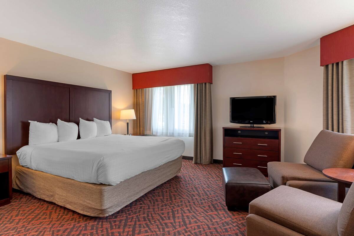 A hotel room with a large bed, a TV, a desk, and a chair.