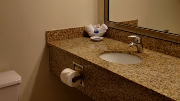 A bathroom with a toilet, sink, and mirror.