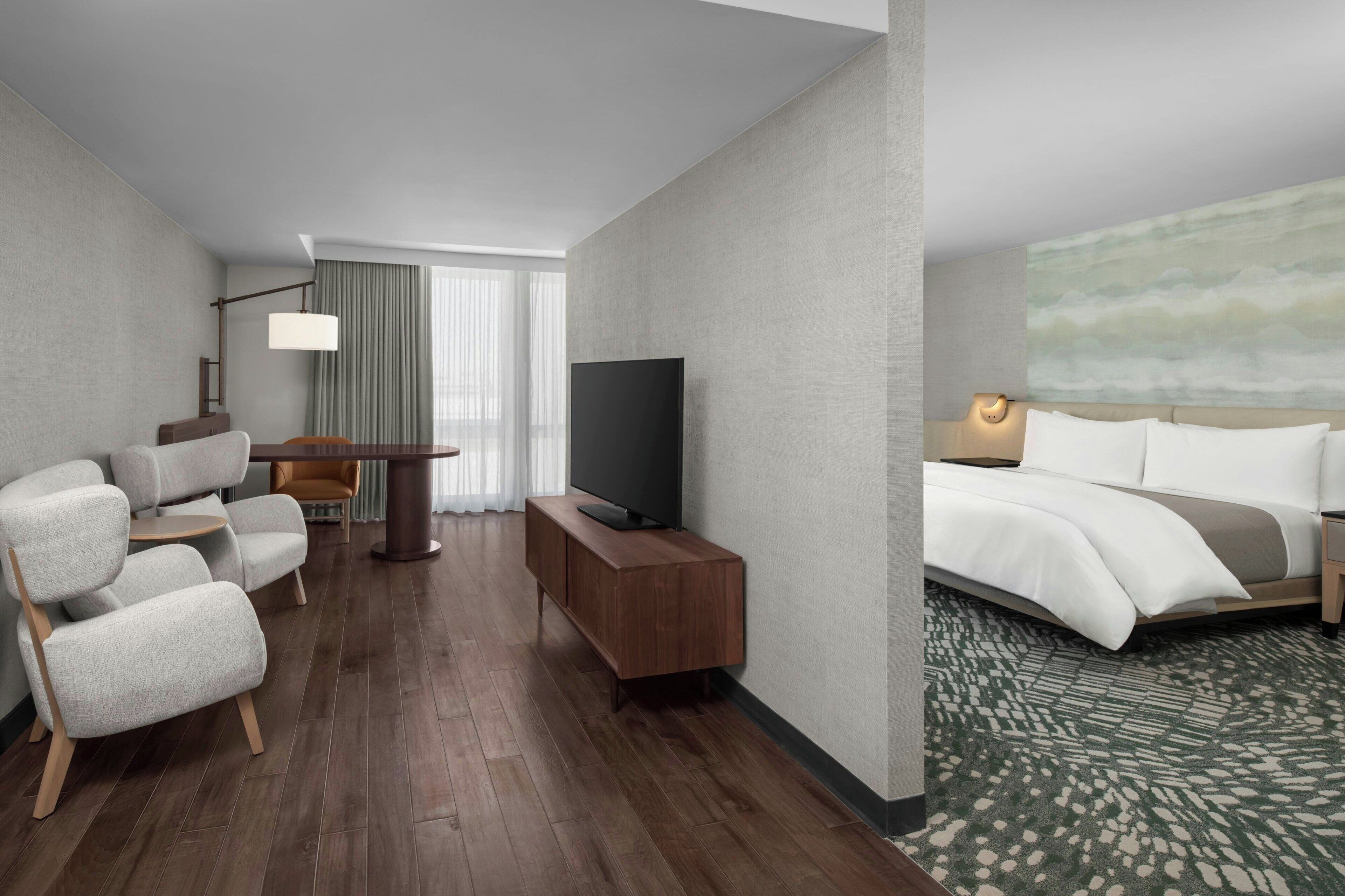 A hotel room with a sofa, TV, bedside table, and a bed with a patterned carpet.