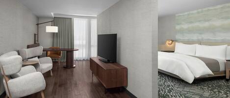 A hotel room with a sofa, TV, bedside table, and a bed with a patterned carpet.