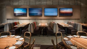 A restaurant with booths and tables, each set with cutlery and glasses.