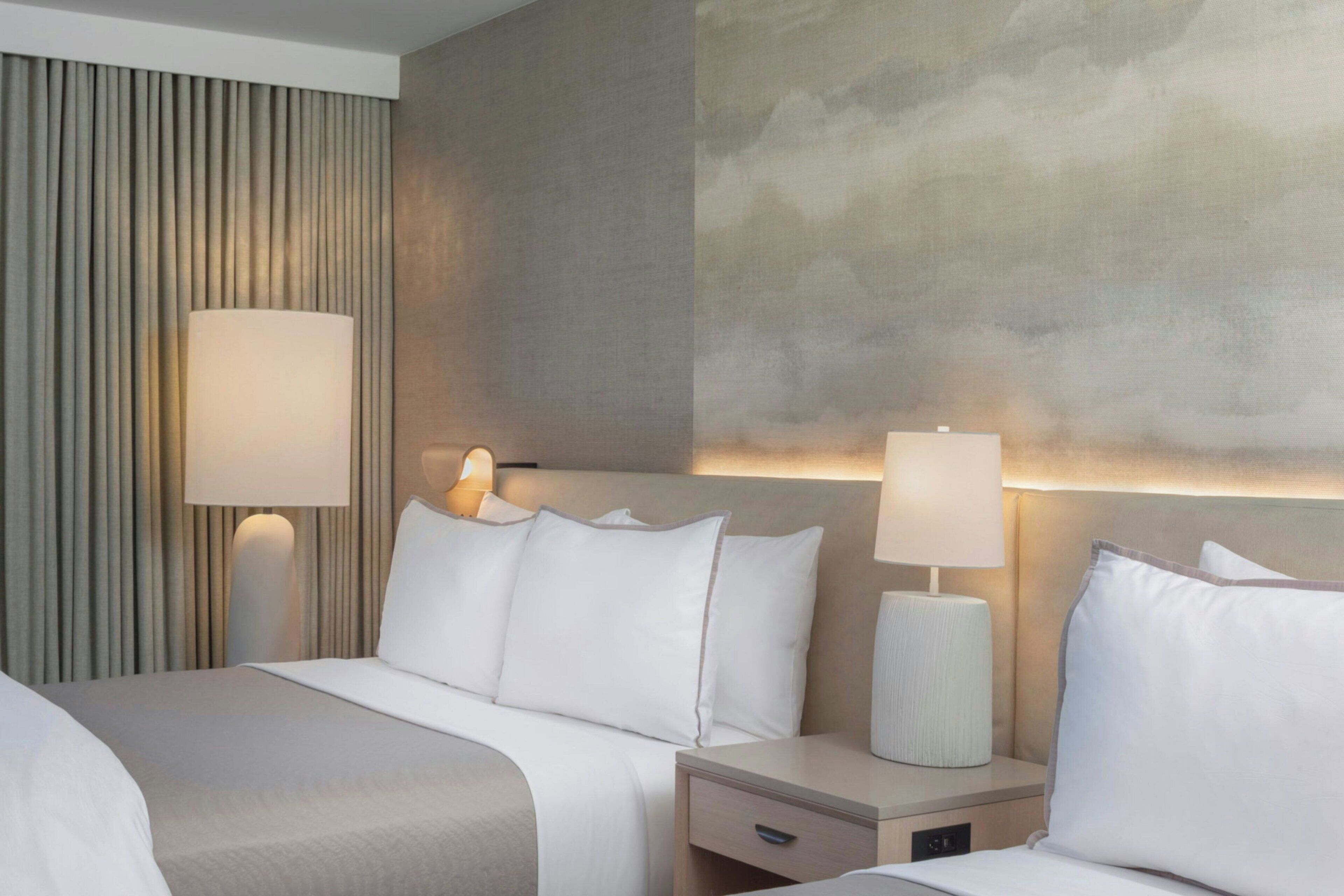 A hotel room with a bed, bedside tables, lamps, and a textured wall.