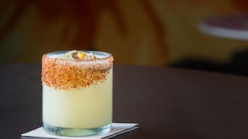 Un cóctel en un vaso con borde de sal, sobre una servilleta en una mesa.