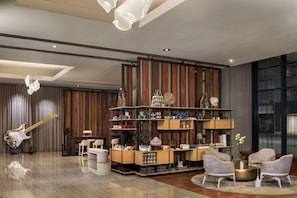 A modern interior with a wooden panel wall, a central shelving unit with various items, and a guitar on the left. - The Westin Cleveland Downtown (Cleveland)