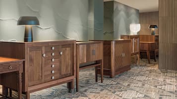 Een hotellobby met houten meubels, een patroon vloer en decoratieve wandkunst met structuur.