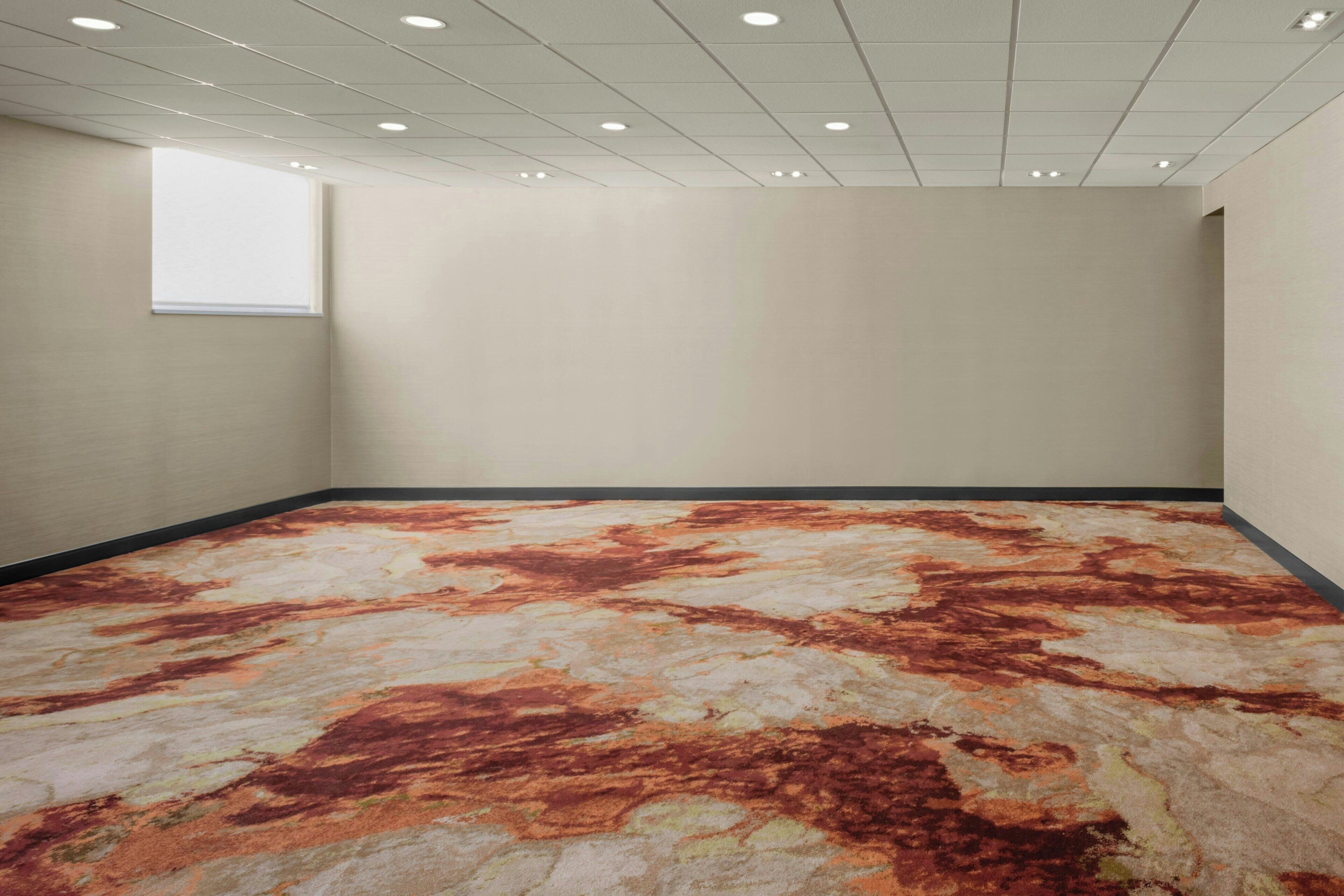 A room with a patterned carpet, a window, and a plain wall.