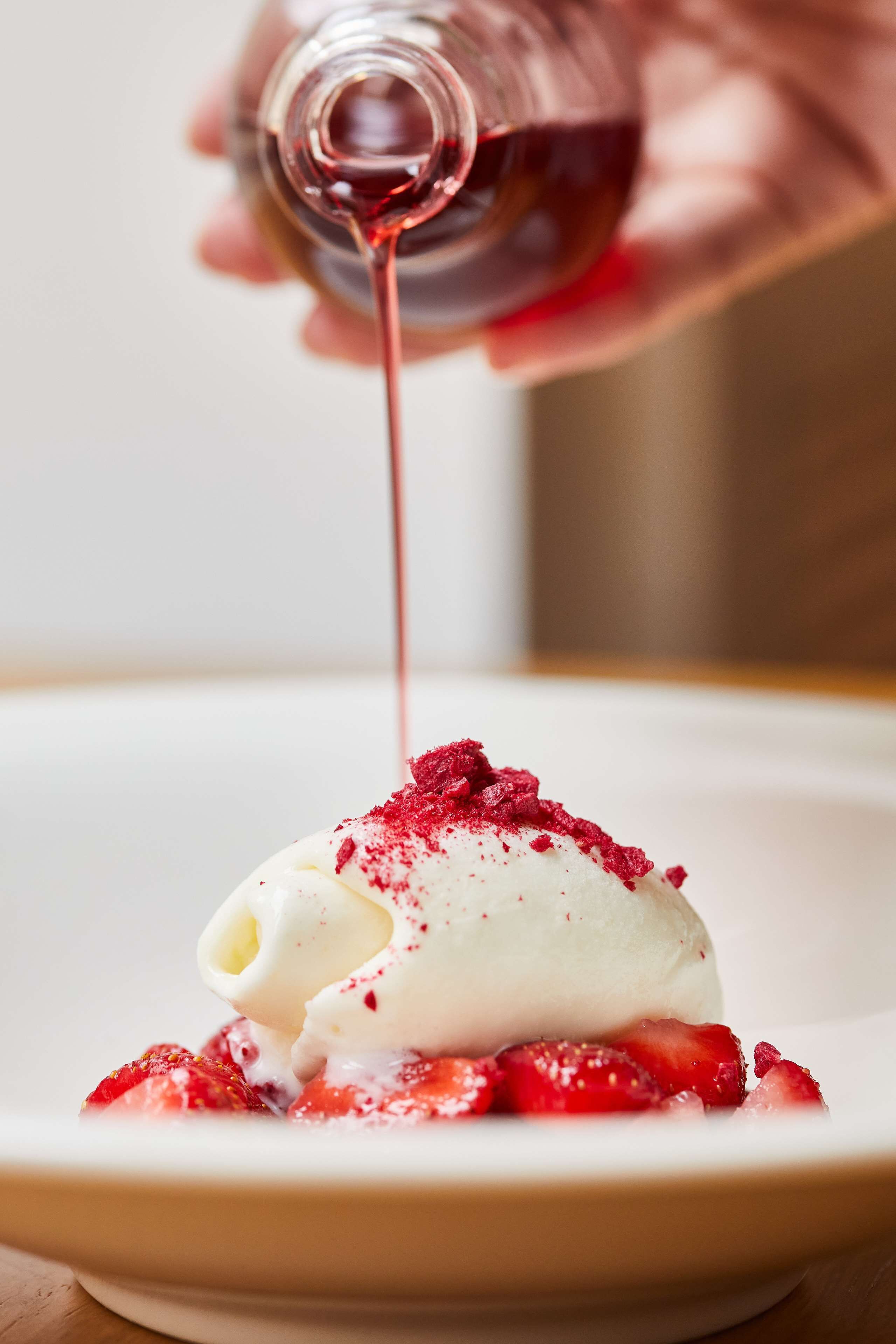 A dessert with a scoop of ice cream topped with strawberries and a drizzle of sauce.