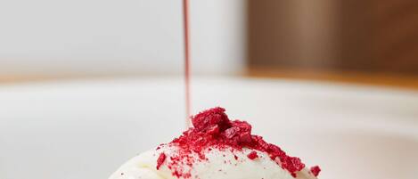 A dessert with a scoop of ice cream topped with strawberries and a drizzle of sauce.