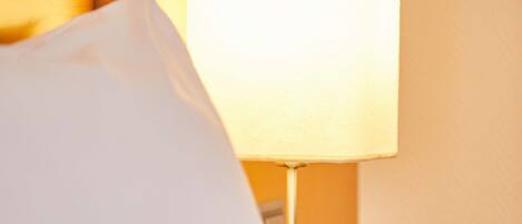 Ein Hotelzimmer mit einem Bett, einem weißen Kissen und einer Nachttischlampe.