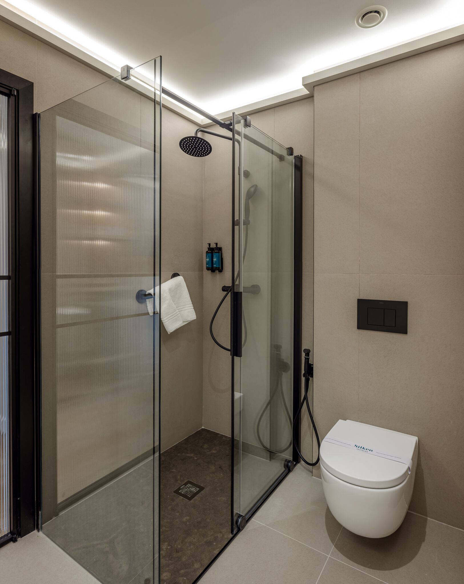 Un baño moderno con ducha de vidrio, inodoro y perchero para toallas.