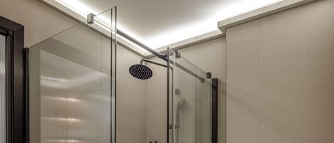 Un baño moderno con ducha de vidrio, inodoro y perchero para toallas.