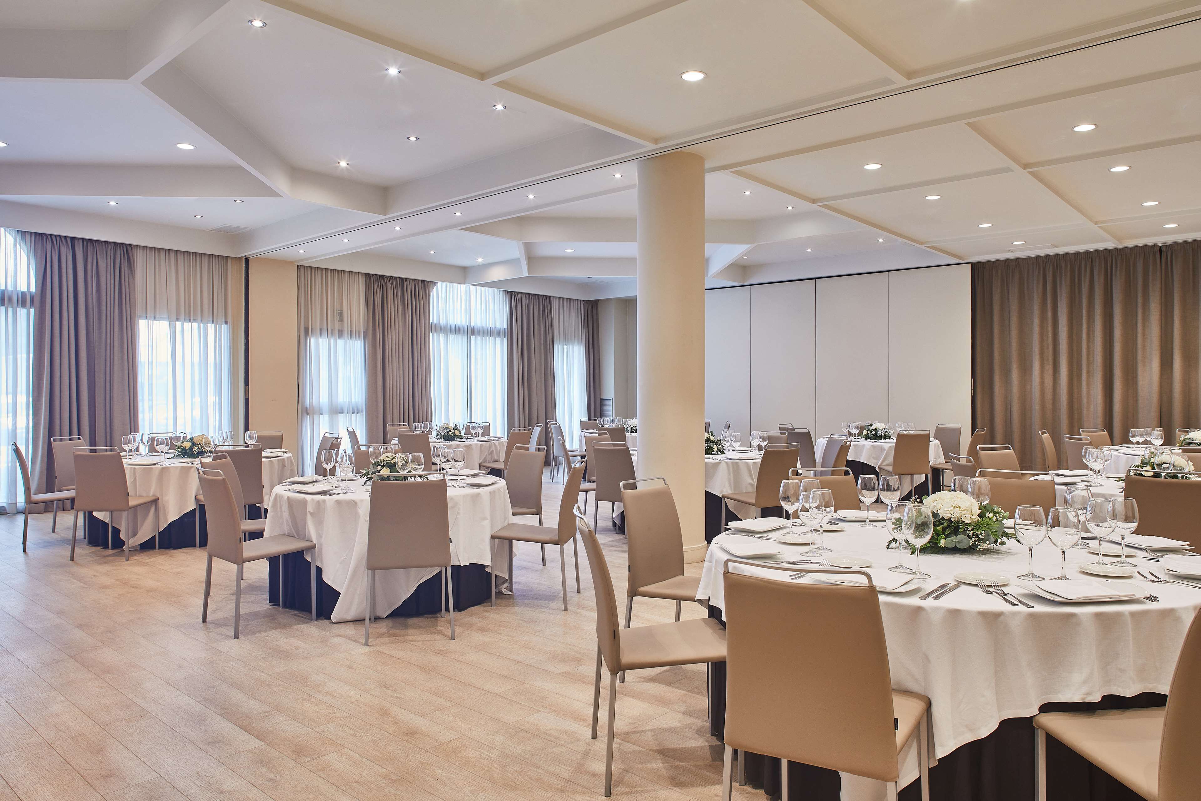 A banquet hall with round tables, chairs, and dining tables set for a formal event.