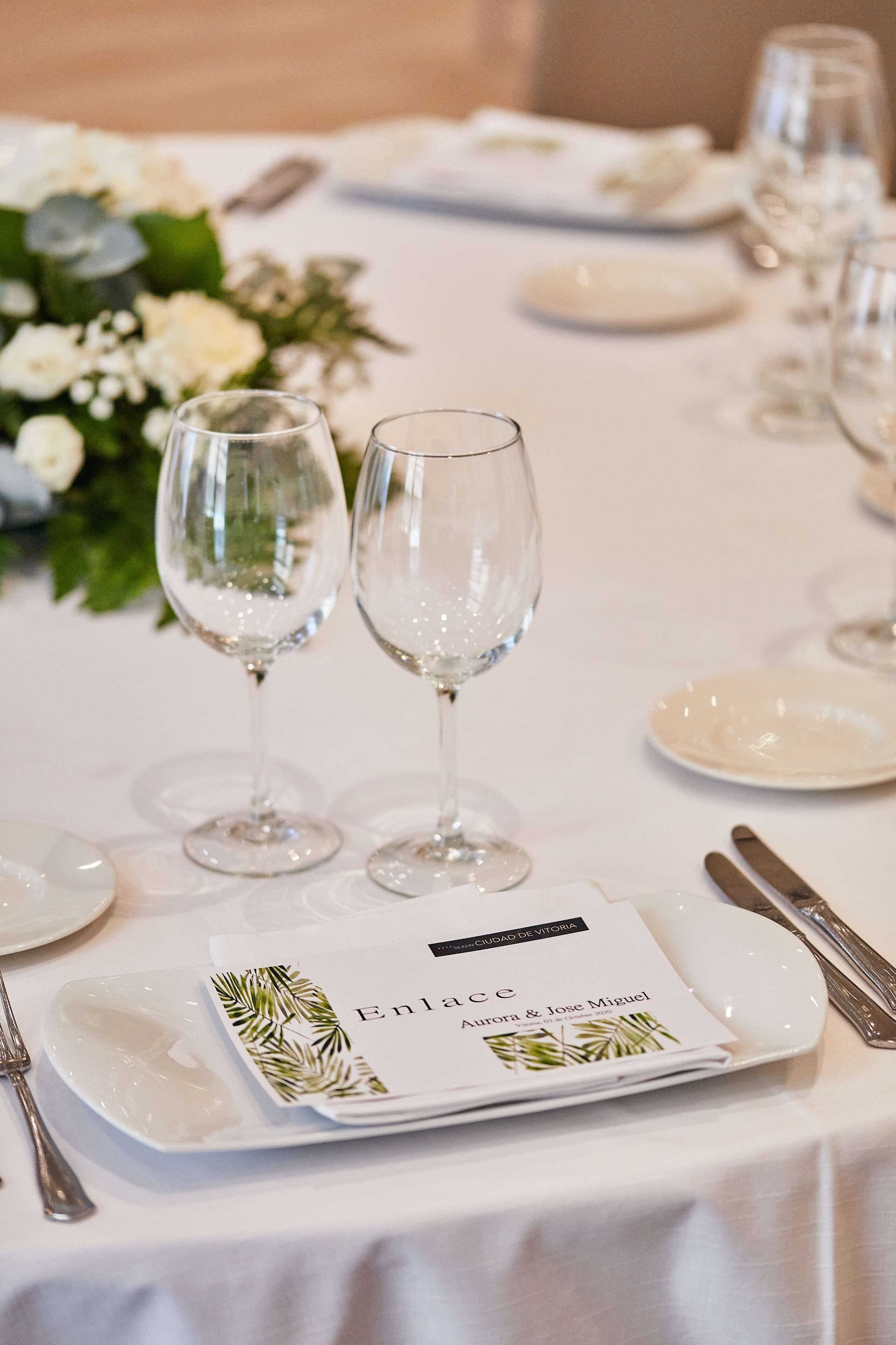 A table set for a formal event with wine glasses, plates, and a menu.