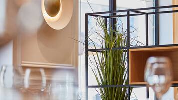 Un espace repas moderne avec une grande fenêtre, une plante en pot et un luminaire contemporain.