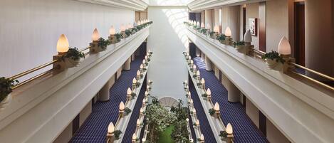 Ein Hotelgang mit einem zentralen Garten, mehreren Etagen und dekorativer Beleuchtung.