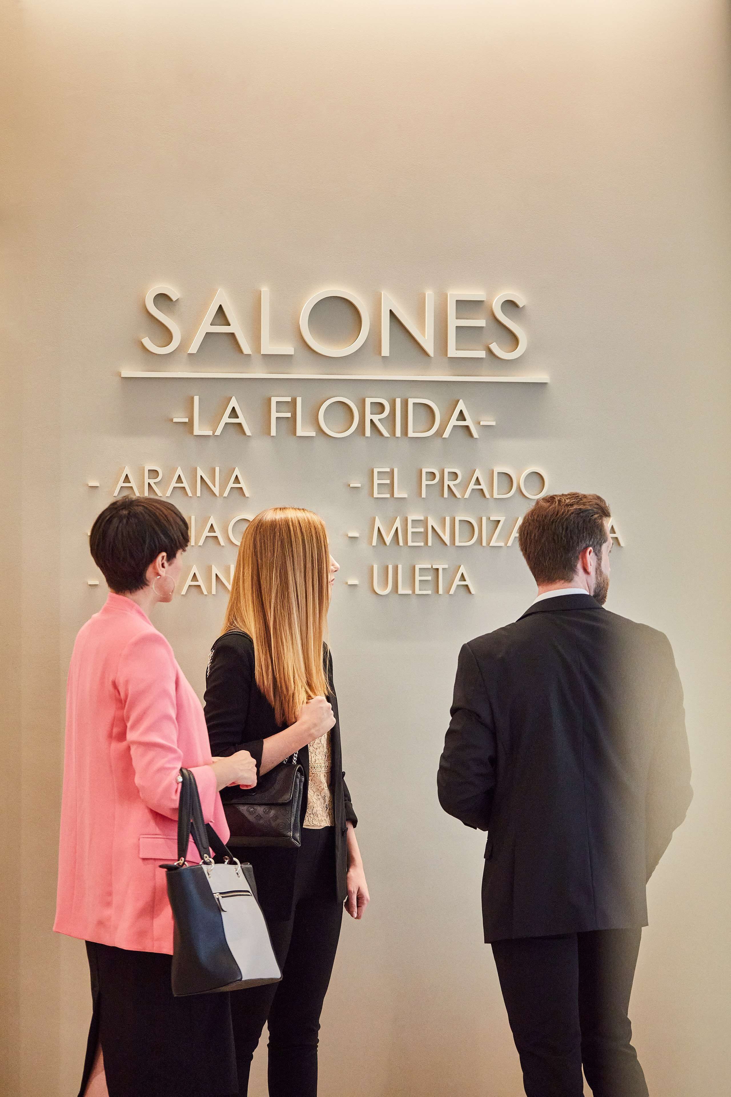 Un groupe de personnes se tient devant un mur sur lequel on peut lire : « SALONES - LA FLORIDA - ARANA - EL PRADO - MENDIZAR - ULETA ».