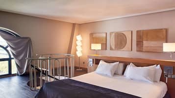 Ett hotellrum med en stor säng, ett skrivbord, en stol och utsikt genom ett fönster.