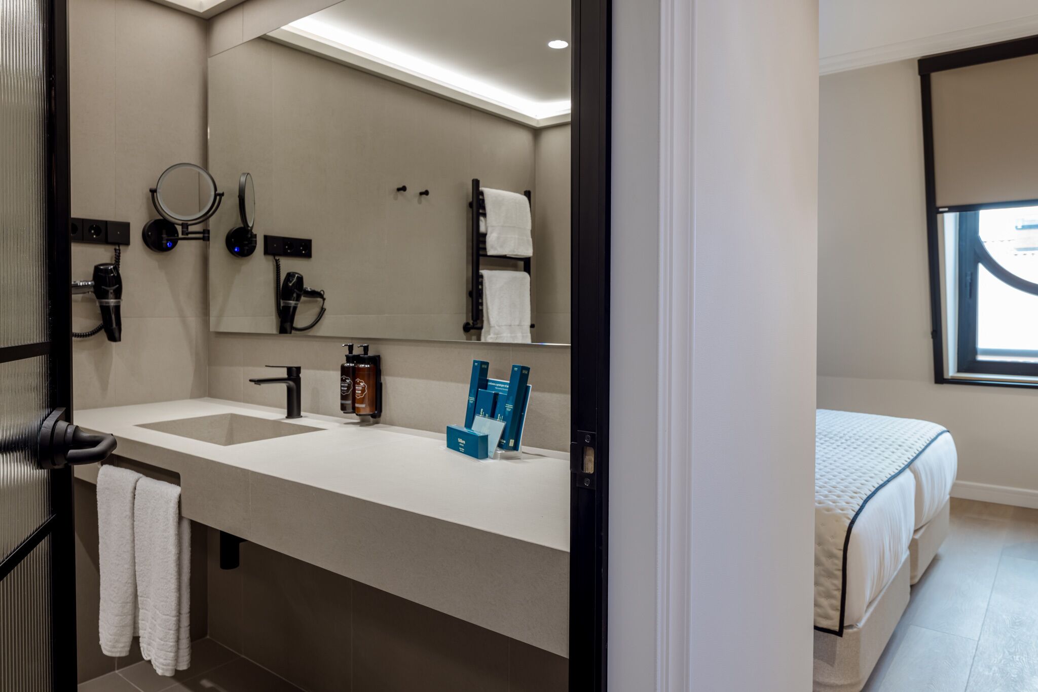 Un baño moderno con lavamanos dobles, un espejo grande y un perchero para toallas.