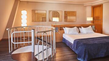 A hotel room with a bed, a desk, and a spiral staircase.