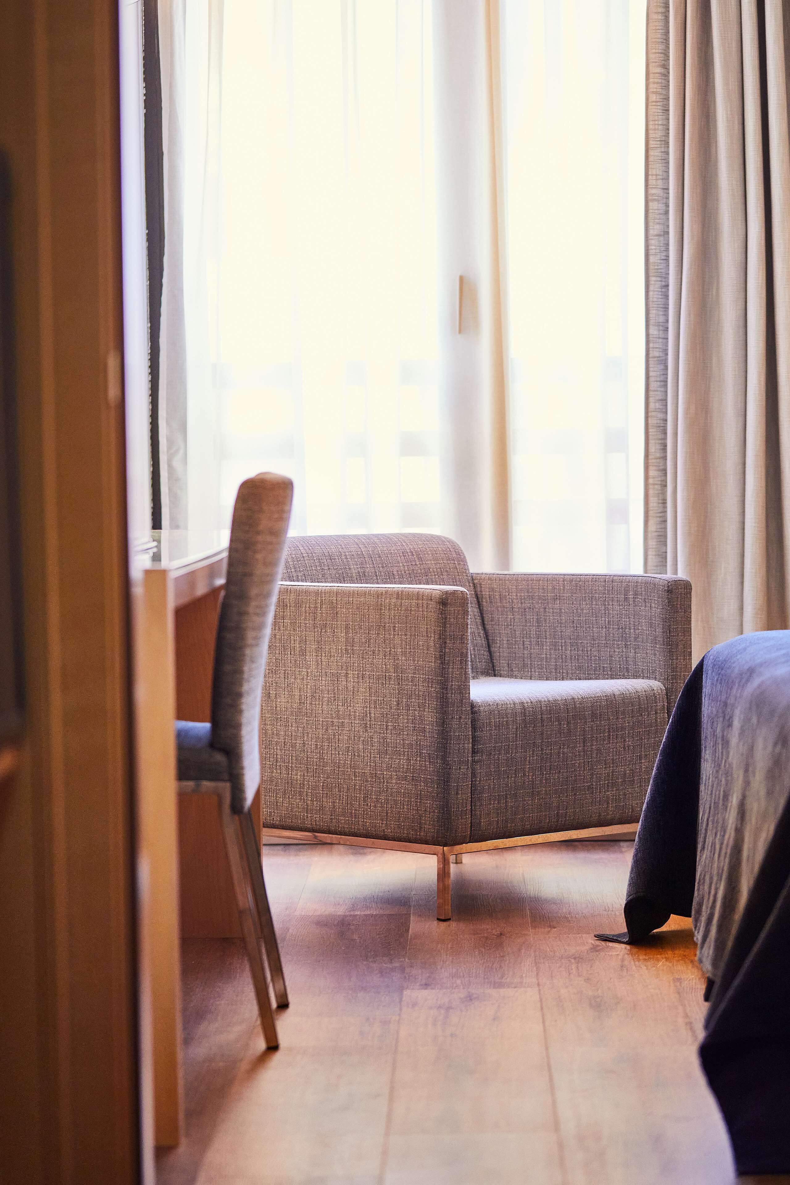 Ein Hotelzimmer mit einer Couch, einem Sessel und einem Bett.