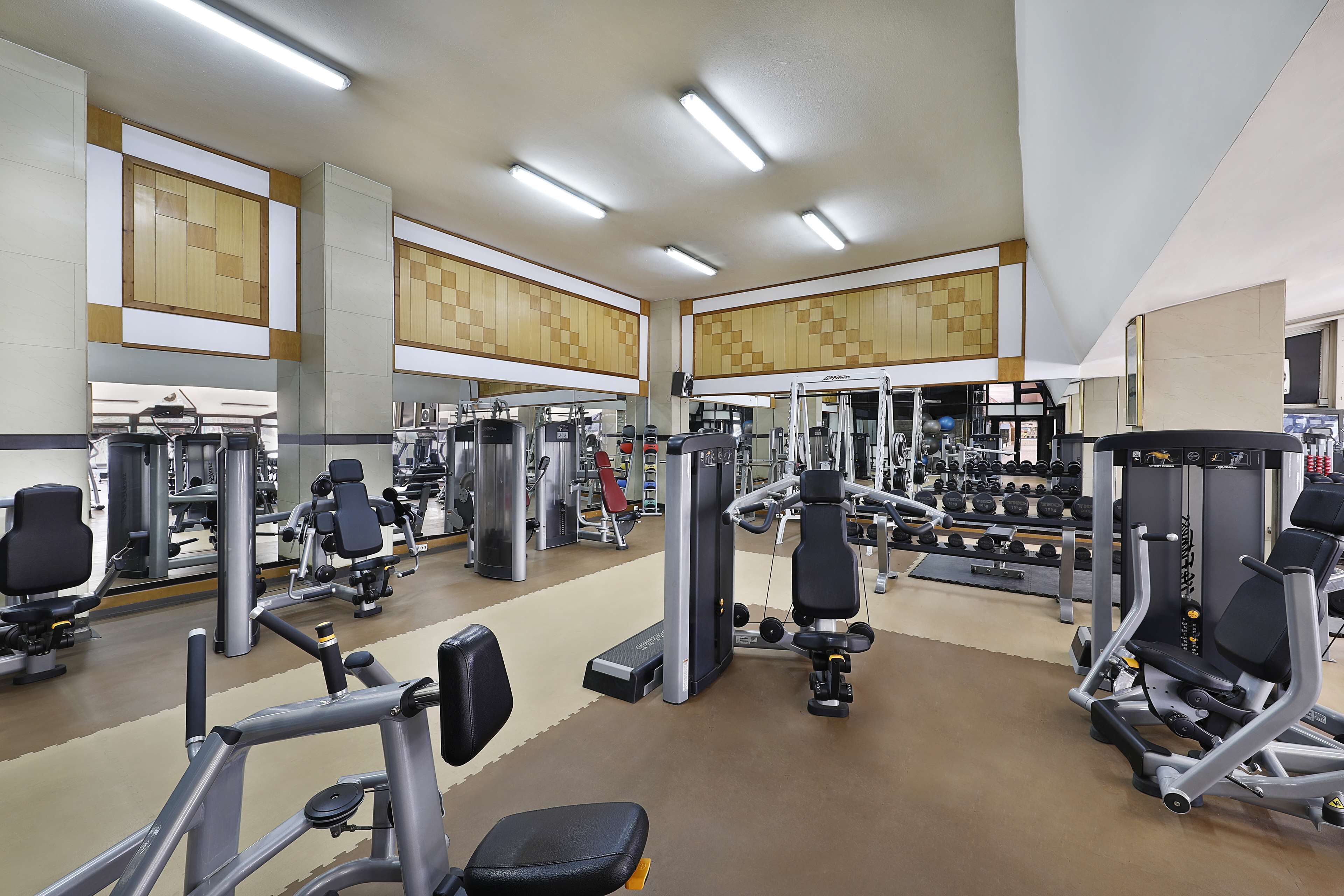 A gym with various exercise machines, mirrors, and weight racks.