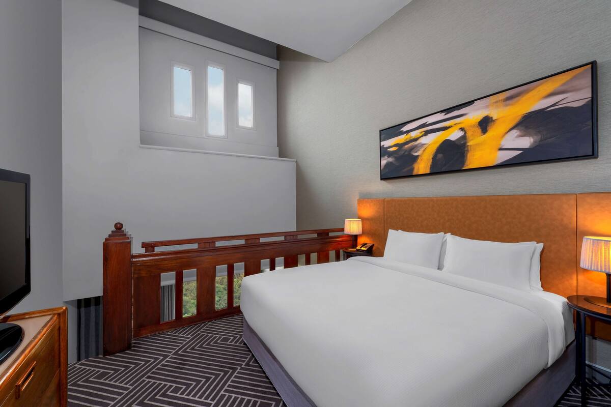 Une chambre d’hôtel avec un lit, une télévision, un bureau et une fenêtre donnant sur un paysage agréable.