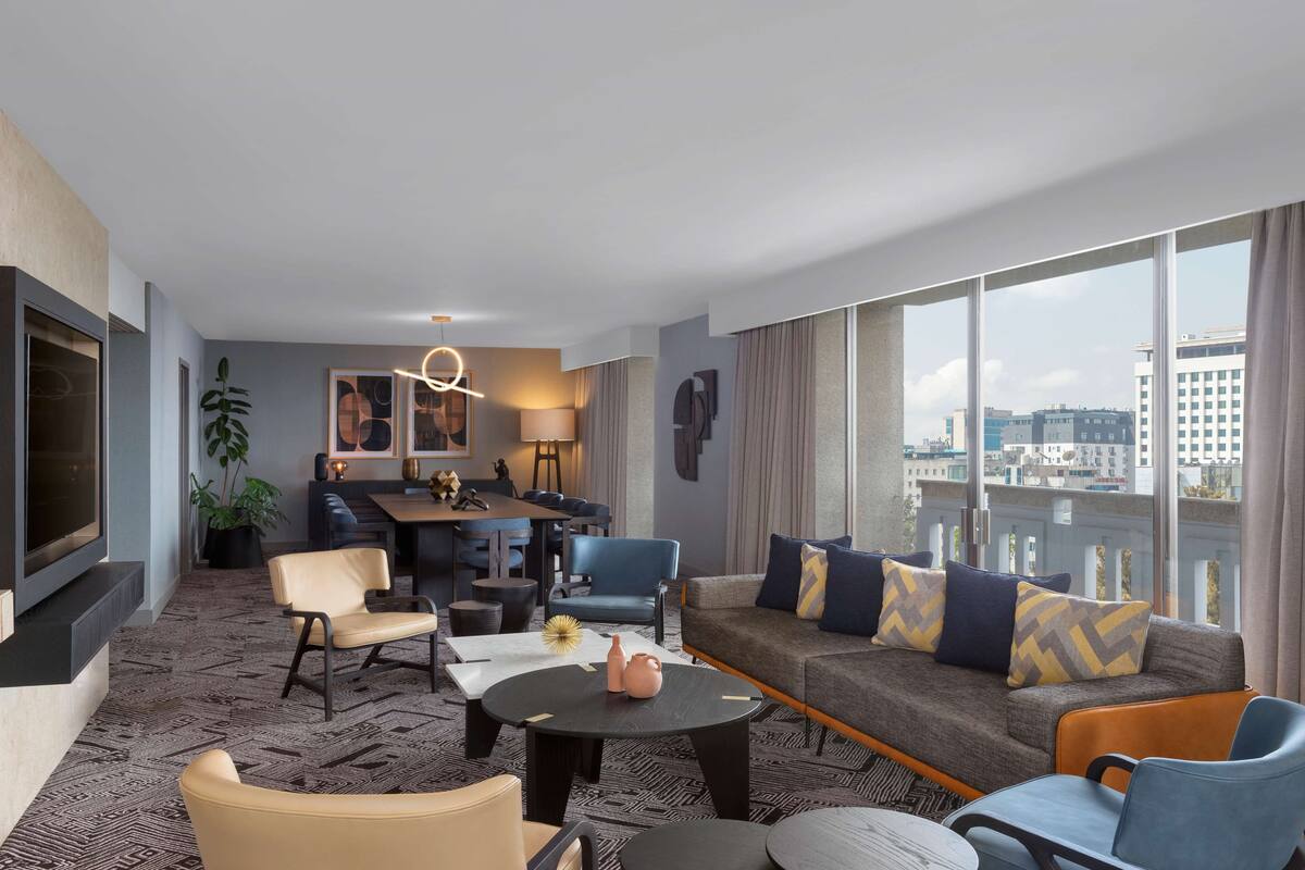 Une chambre d’hôtel moderne dotée d’une grande fenêtre, d’un canapé, d’un coin repas et d’un téléviseur.