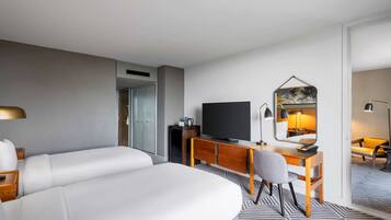 A hotel room with a bed, a desk, a chair, a television, and a mirror.