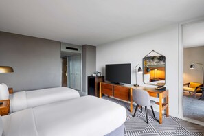 A hotel room with a bed, a desk, a chair, a television, and a mirror.