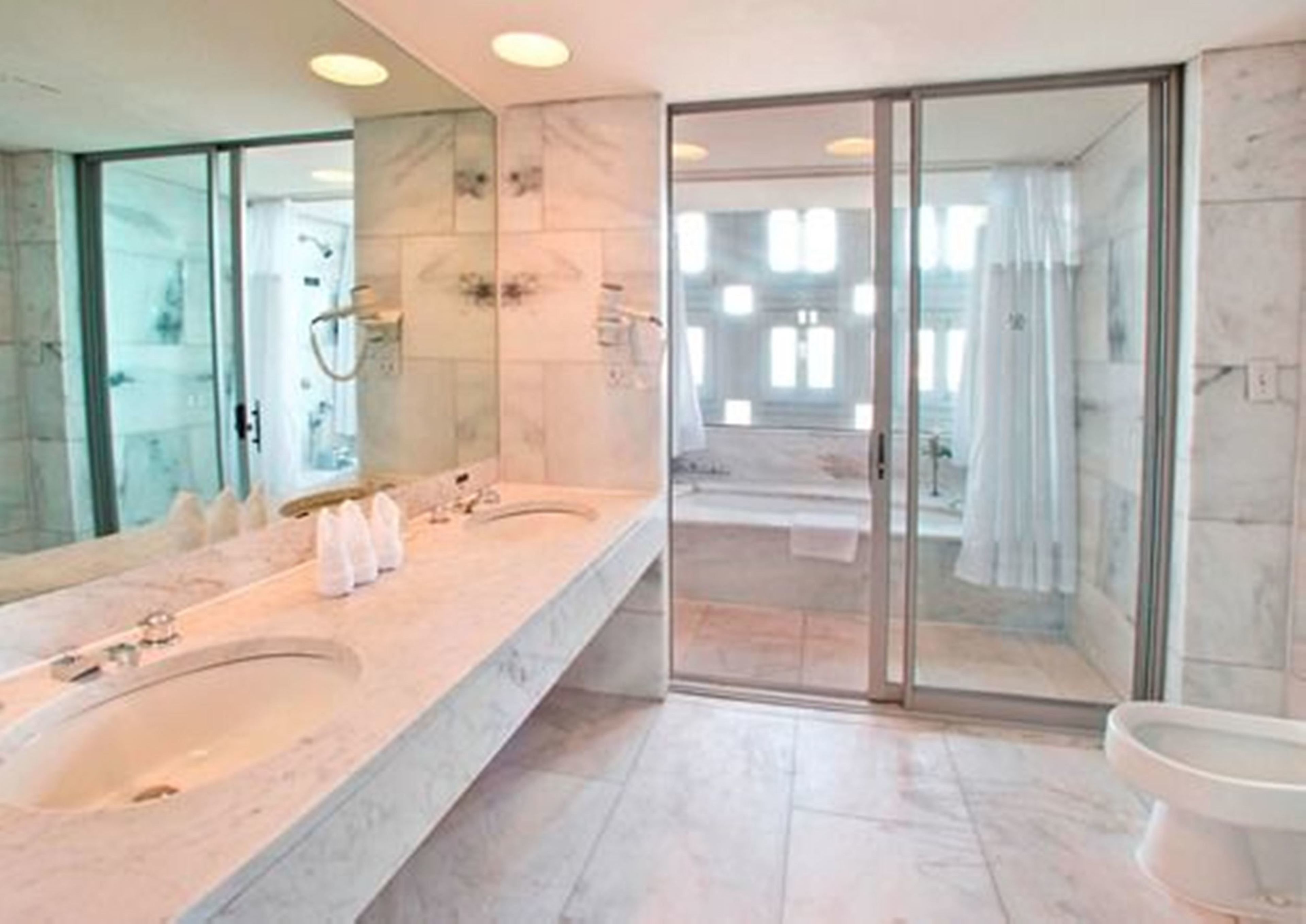 Een moderne badkamer met twee wastafels, een douchecabine van glas en een grote spiegel.