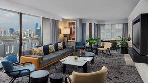 A modern hotel room with a large window offering a city view, a sofa with cushions, a coffee table, and a TV. - Hilton Addis Ababa (Addis Ababa)