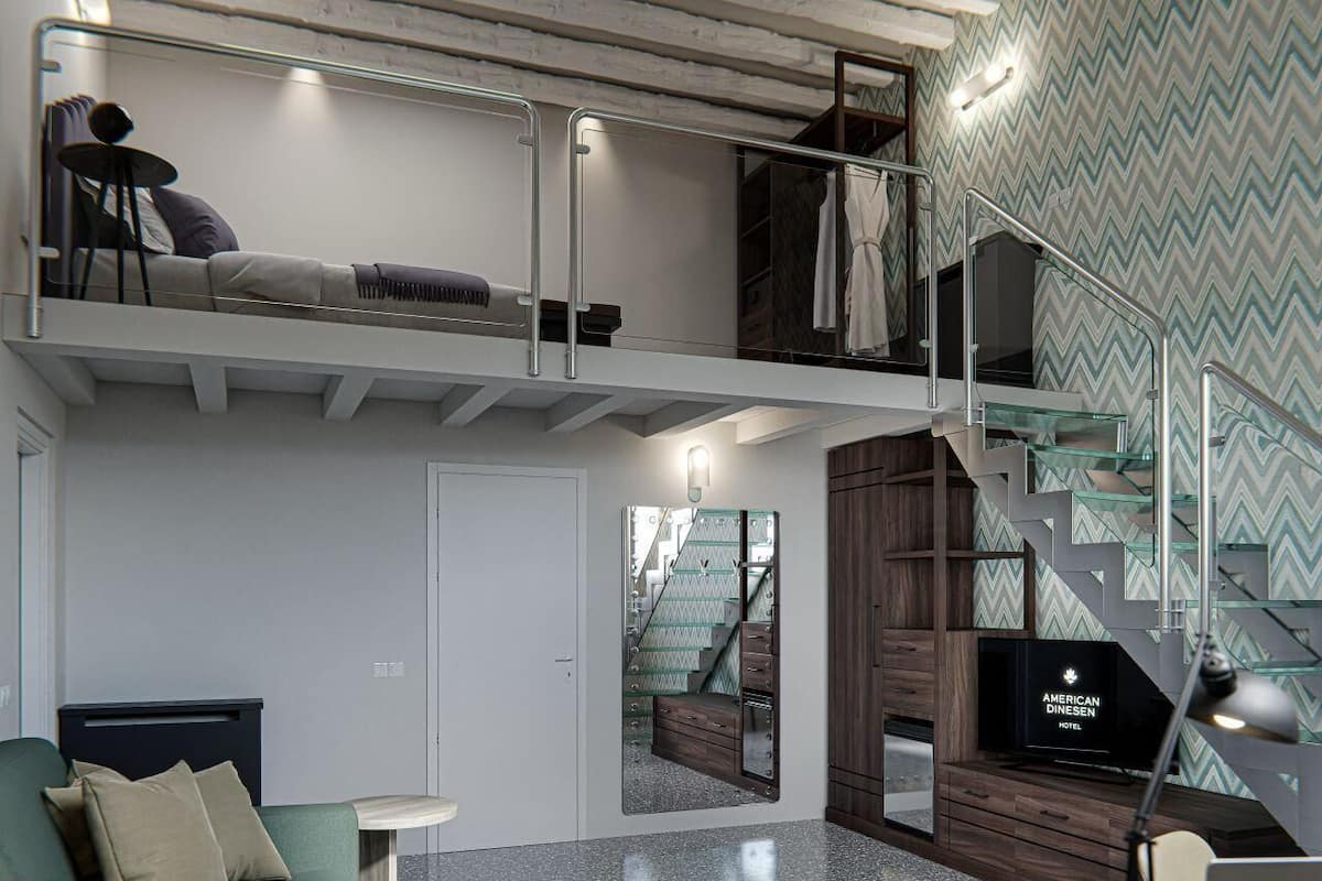 A modern hotel room with a green sofa, a small table, a TV, and a staircase with a mirrored wall.