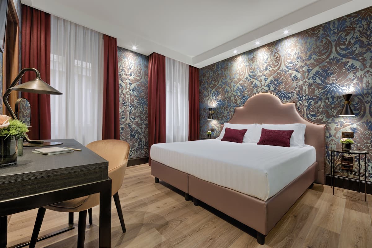 A modern bedroom with a large bed, a desk, and a chair.