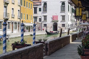 Un canal con una góndola, edificios con balcones y un puente.