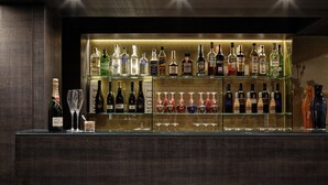 A bar area with multiple shelves of liquor bottles and glasses. - Hotel American Dinesen (Venice)