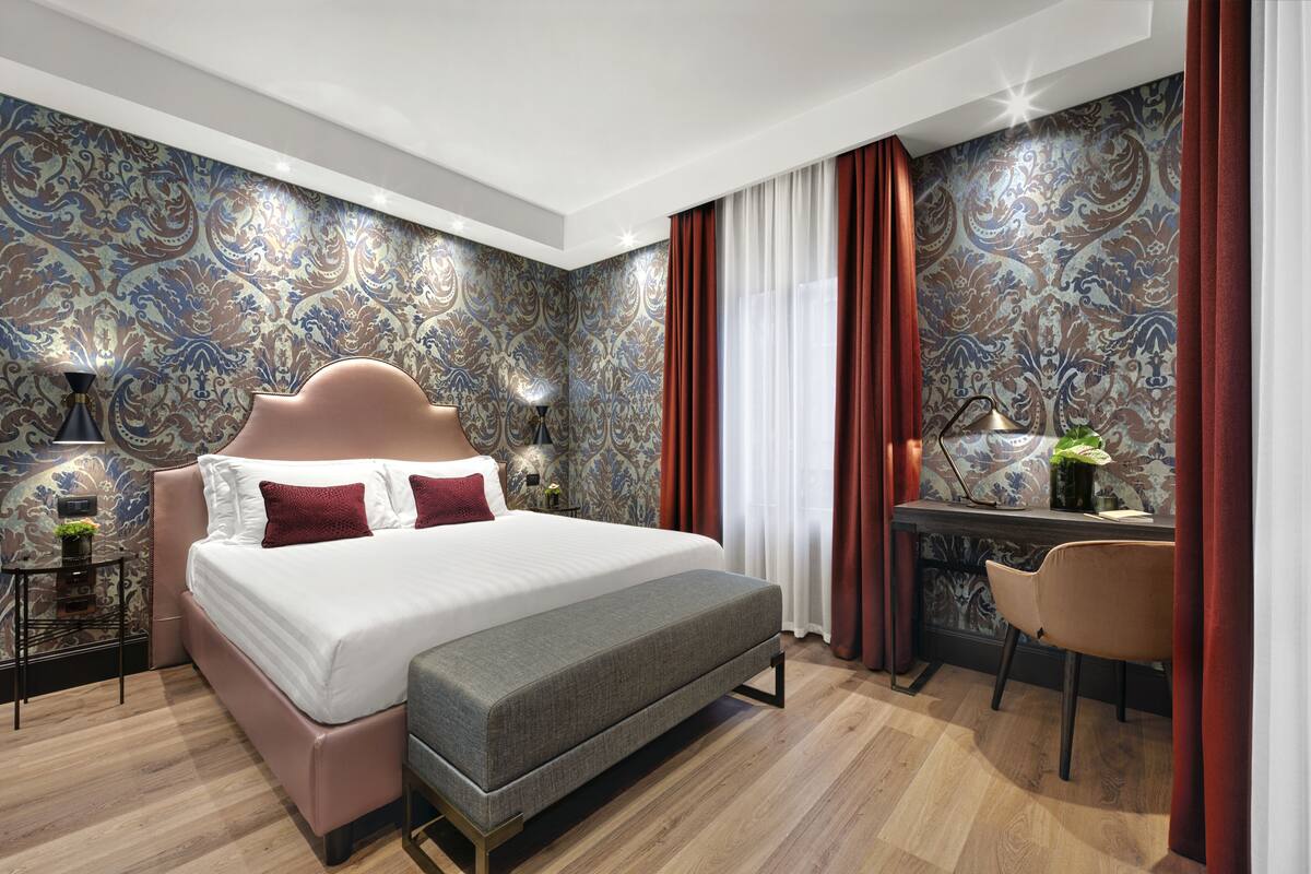 A modern bedroom with a large bed, a desk, and a chair.