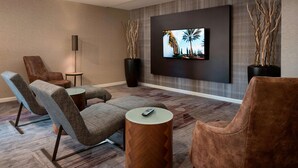 A modern living room with a flat-screen TV mounted on the wall, two large vases, and a sofa with a coffee table.
