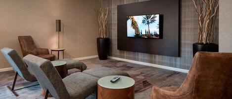 Una sala moderna con una televisión de pantalla plana montada en la pared, dos jarrones grandes y un sofá con una mesita de centro.