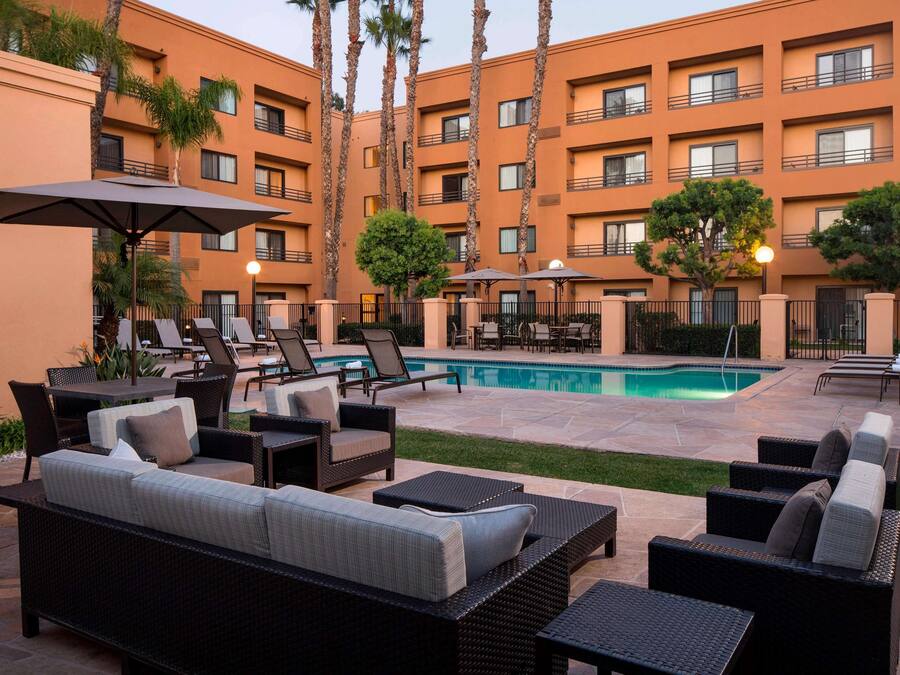 A poolside area with lounge chairs, a pool, and a building with balconies.