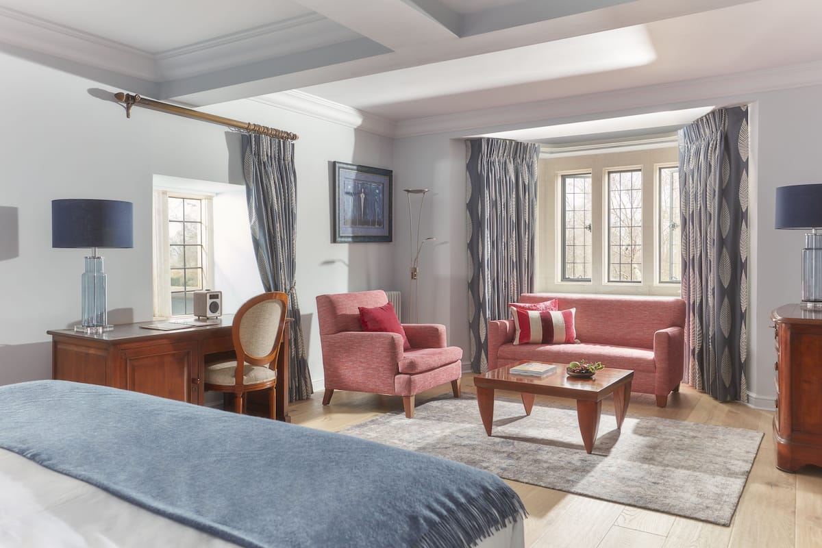 A well-lit room with a bed, a desk, a chair, a sofa, and a coffee table.