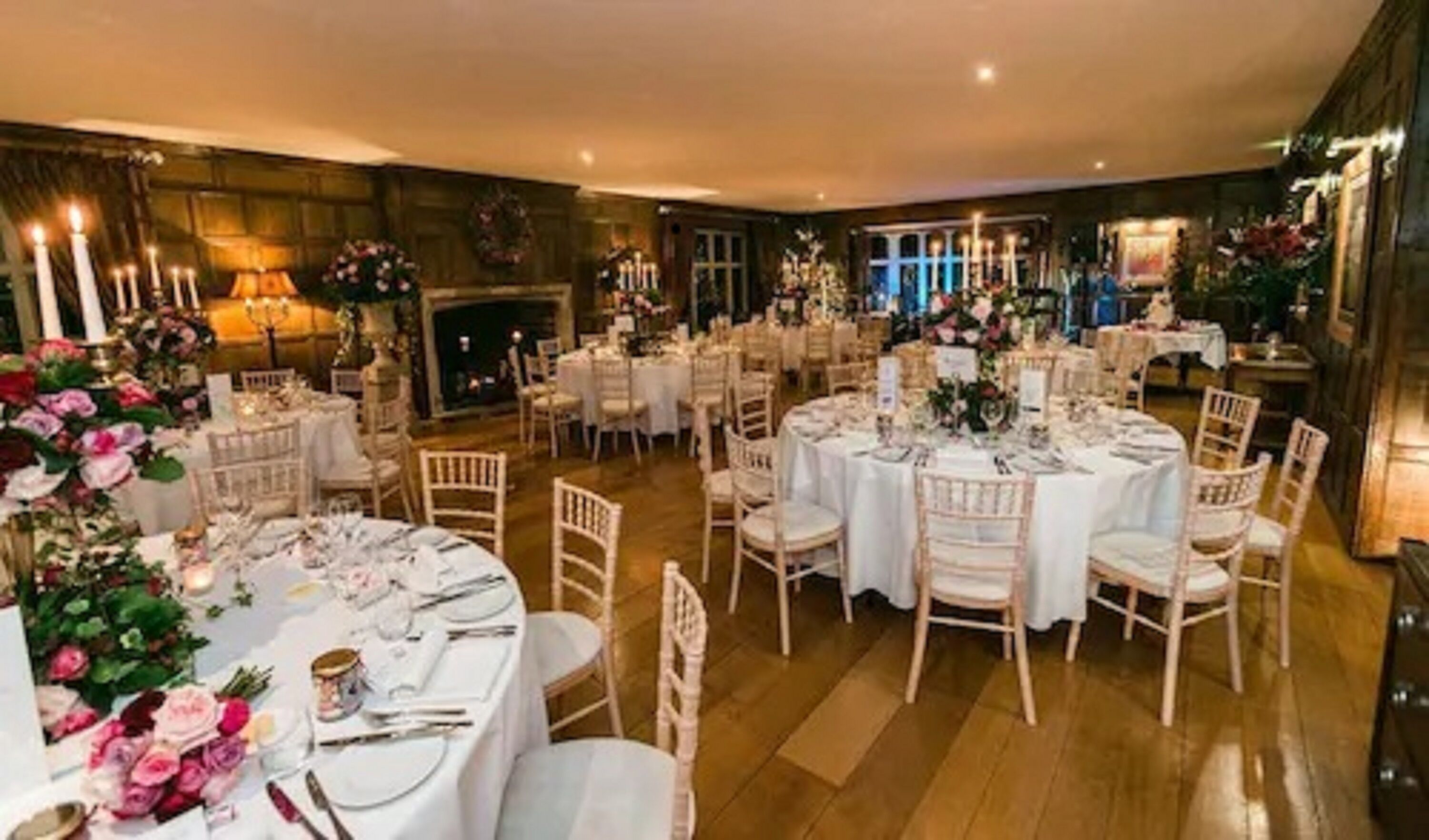 Un comedor formal con mesas redondas, sillas blancas y arreglos florales.