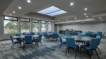Un salón de conferencias con varias mesas y sillas, ventanas amplias y tragaluces.