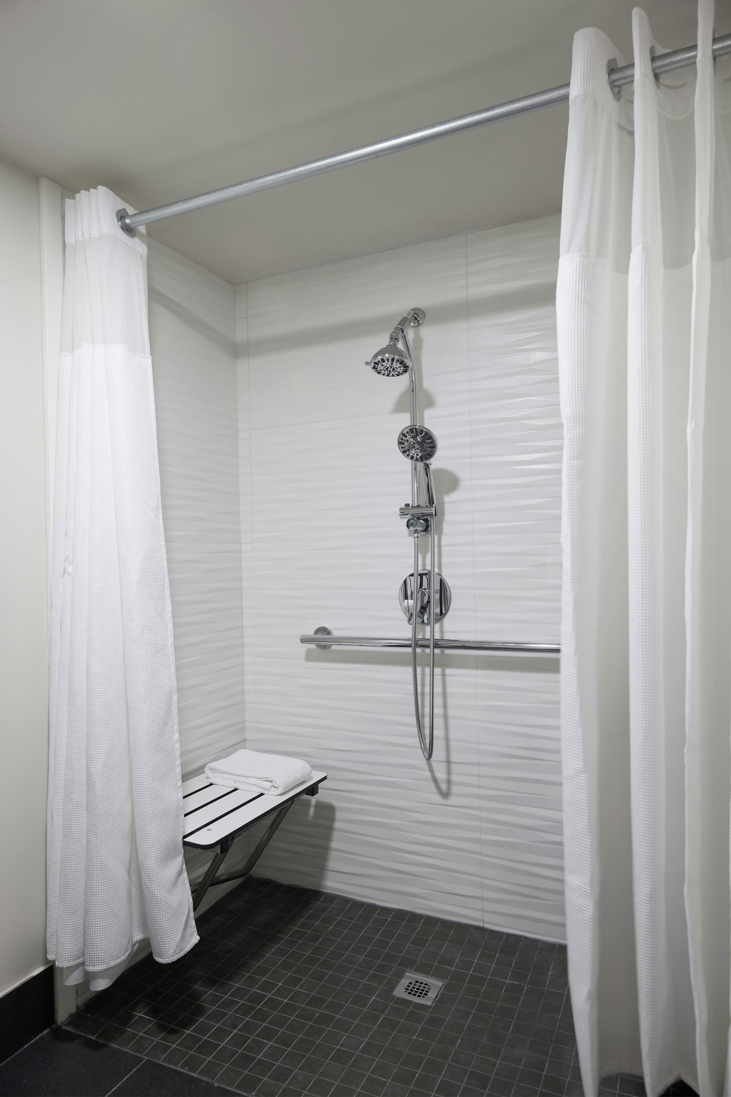 A shower area with a glass door, a towel rack, and a showerhead.